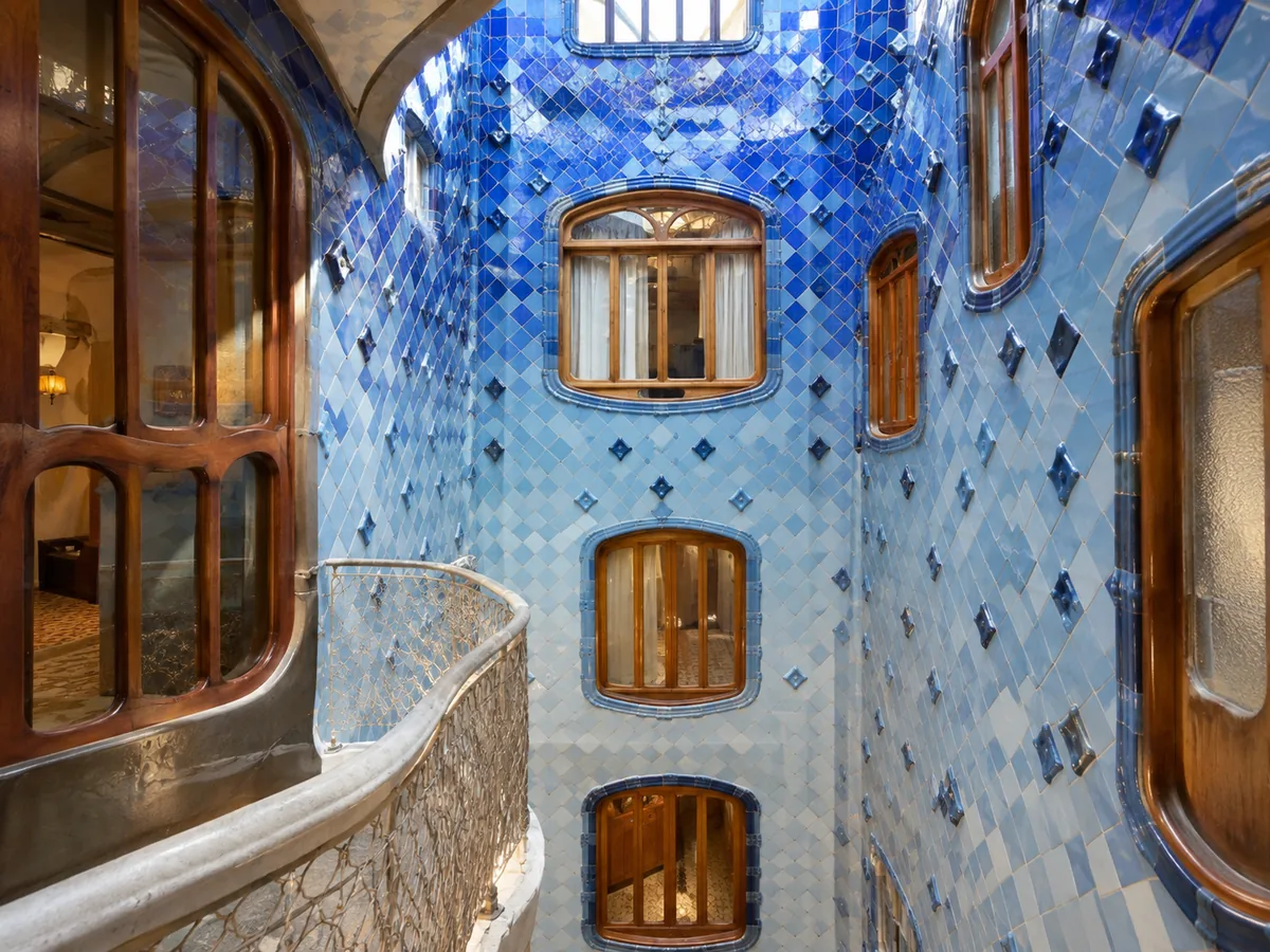 Ein Lichthof mit blauen Keramikfliesen und geschwungenen Holzfenstern